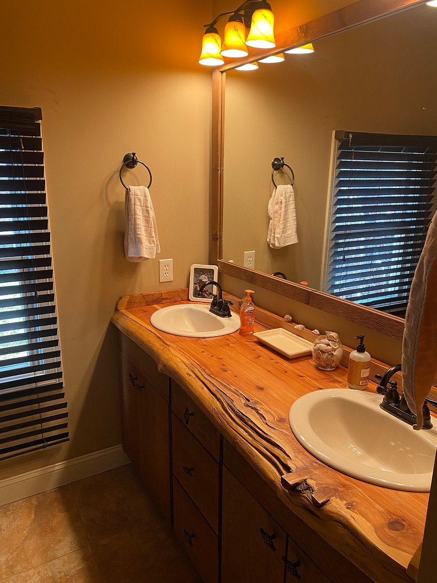 Bathroom has a double vanity and large walk-in glass door shower with rain spout.