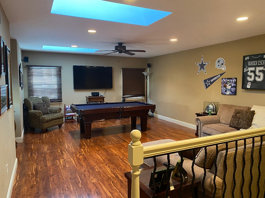 Large living room offers a comfortable sectional couch, pool table and wall mounted 70 inch smart TV. The room has lots of natural light with cathedral a ceiling, skylights and a ceiling fan.