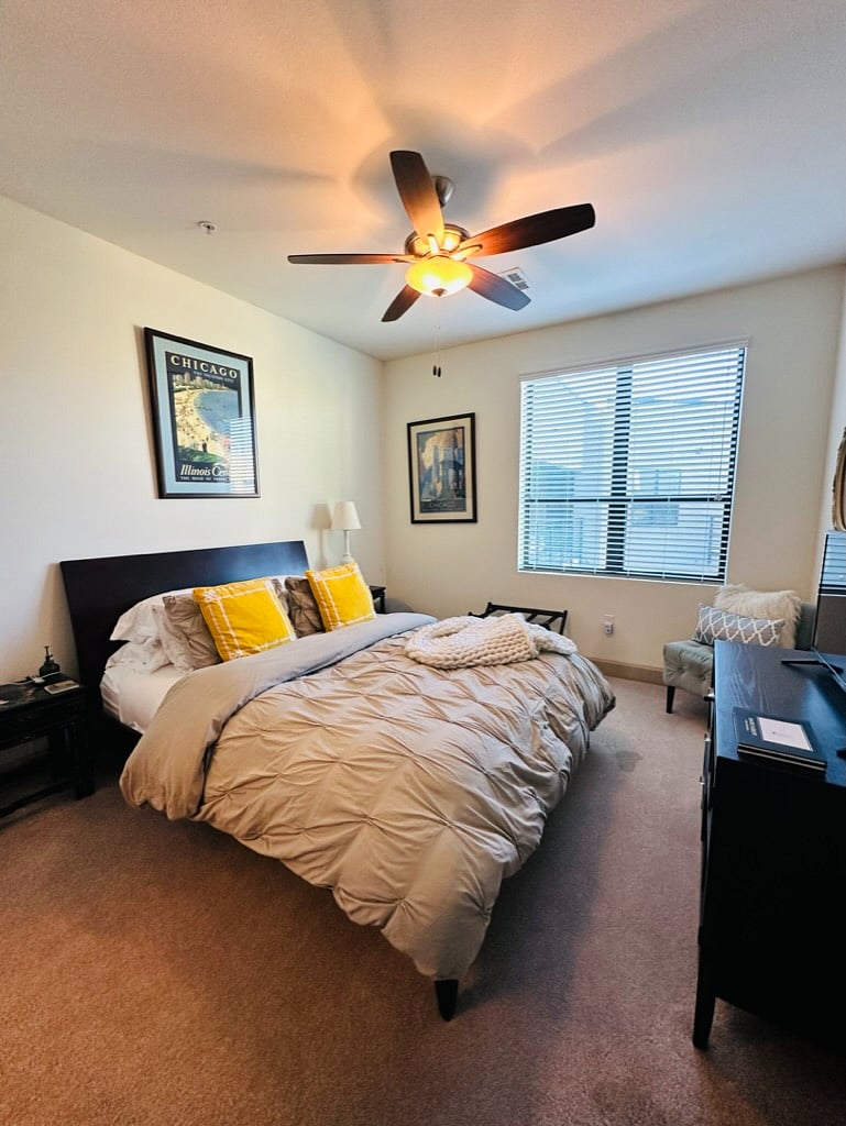 Bedroom has a queen bed, small dresser and a television with Apple TV.