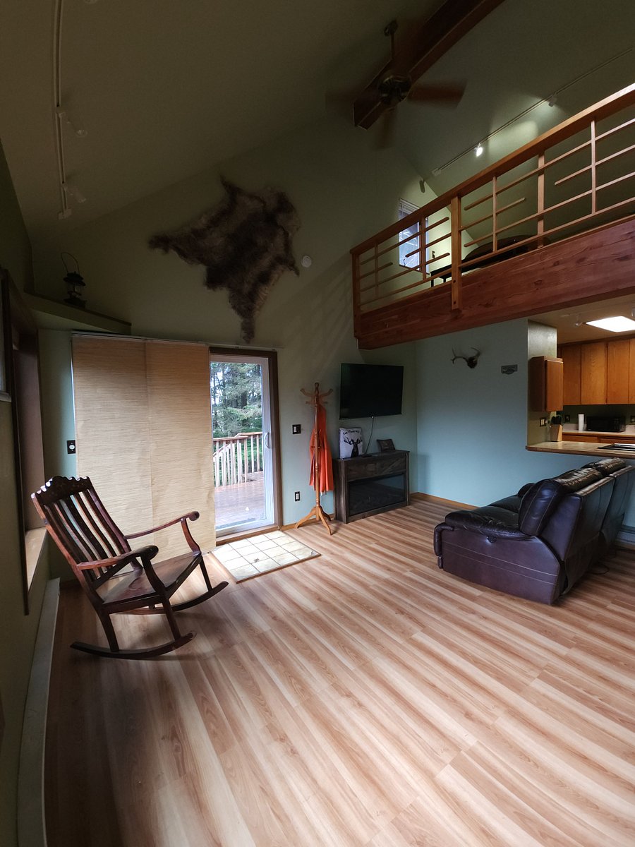 Main living area with antique rocking chair, leather sofa, wall mounted smart TV, and fireplace. Slide in door locks and has keys with blackout bamboo curtains