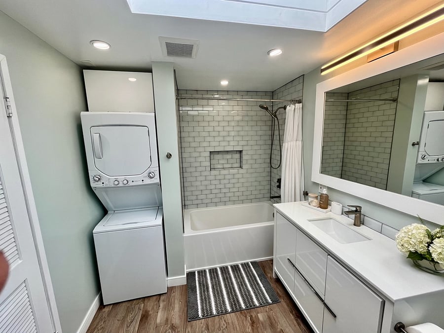 In unit washer-dryer in bathroom nook with storage above.