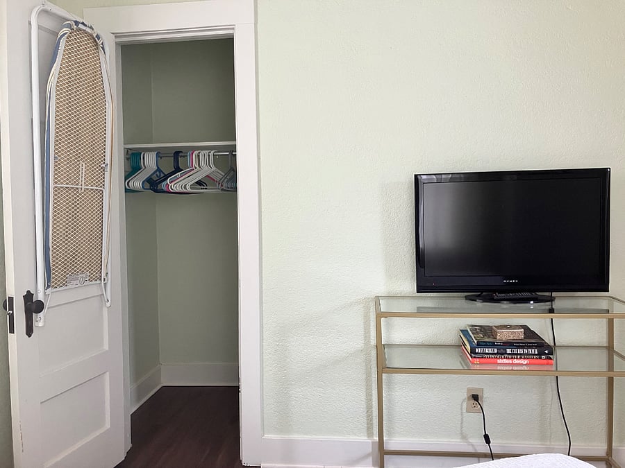 Large closet with plenty of storage on the floor and above, an iron and ironing board.