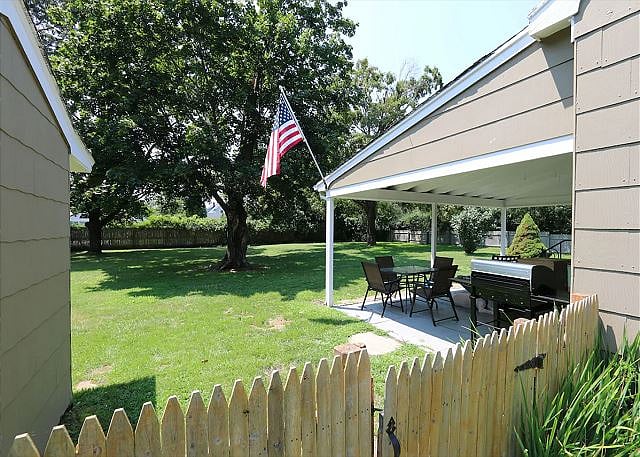 Patio, overlooking a vast, fenced, lush green yard.
