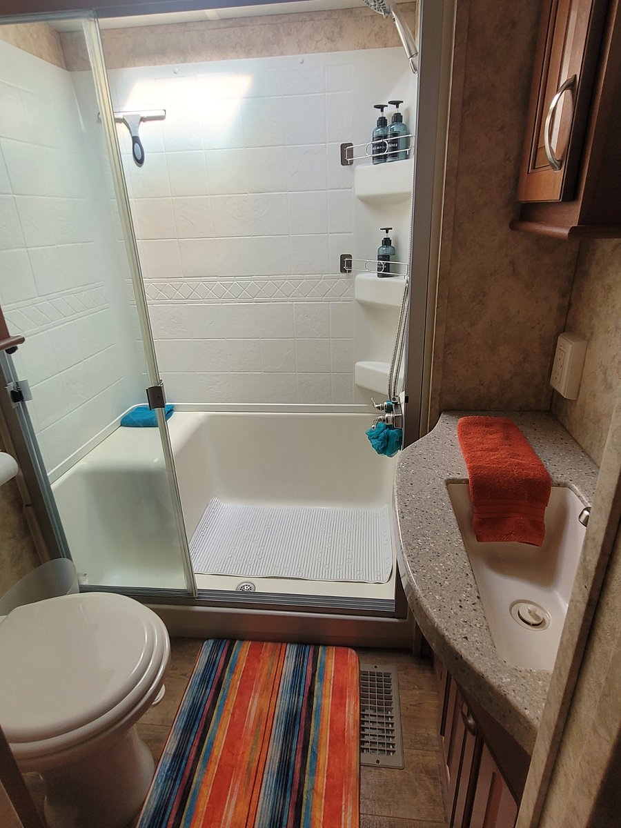 Full sized shower, shower seat, corner cubby for hygiene items.