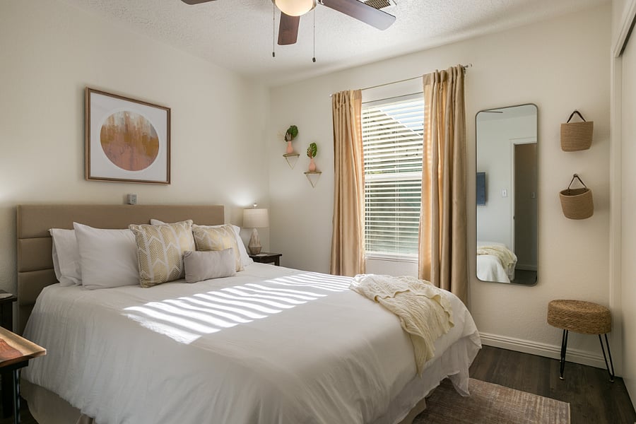 Relax in this serene bedroom, designed for comfort and tranquility. The room features a plush queen-sized bed with soft linens and a variety of cozy pillows, perfect for unwinding after a long day. Natural light flows in through large windows, highlighting the warm, neutral tones and subtle decor. Thoughtful touches like hanging planters, a stylish full-length mirror, and woven wall baskets add a modern, earthy vibe. This space is ideal for a restful nights sleep and a rejuvenating stay.