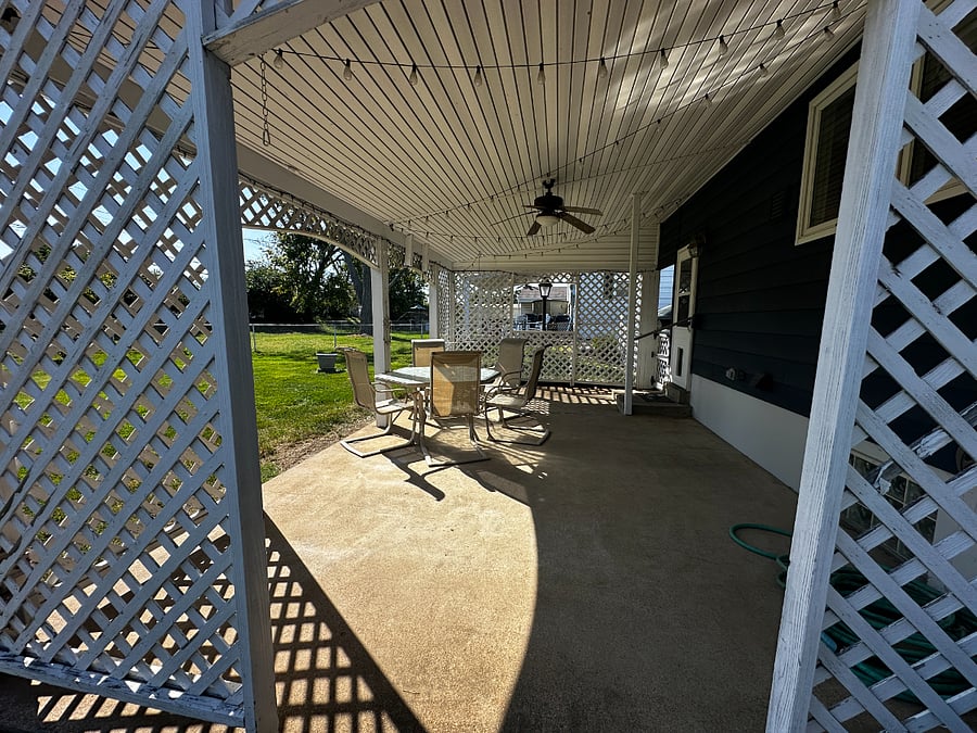 Covered Patio with table and chairs. Flat fenced in backyard.