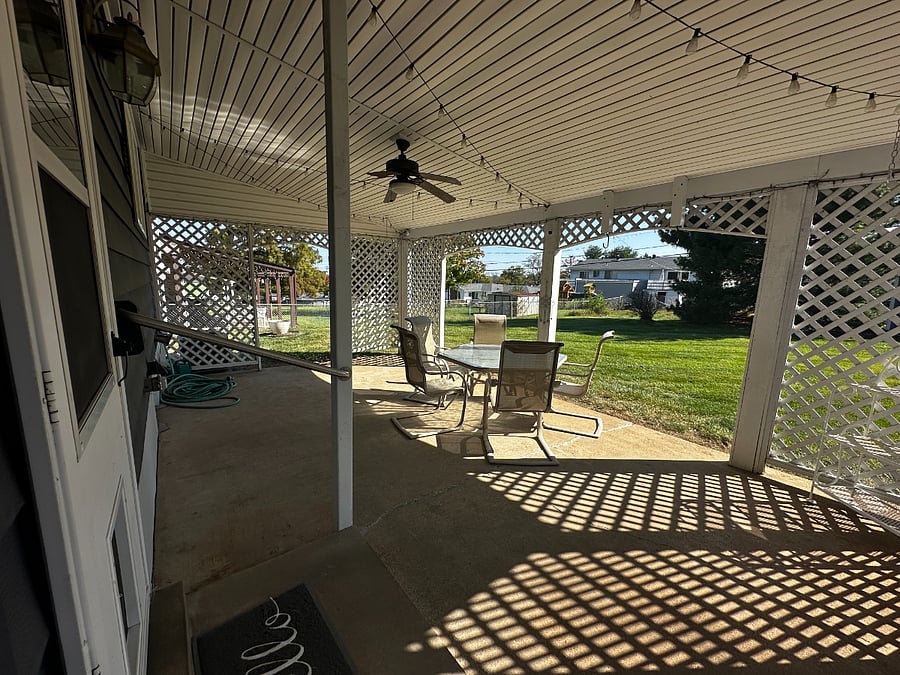 Covered Patio with table and chairs. Flat fenced in backyard.