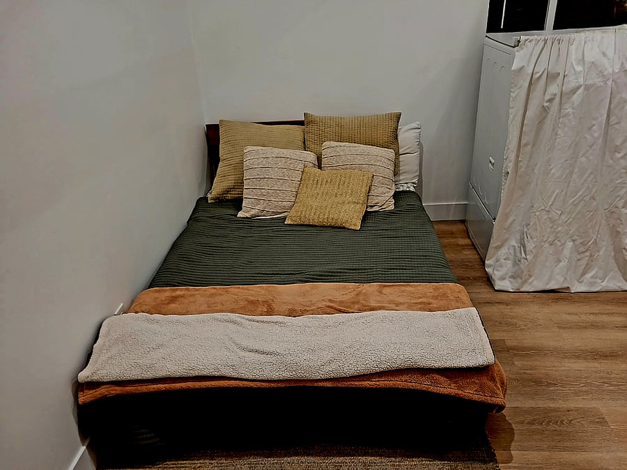 Full bed adjacent to washer-dryer in bedroom.