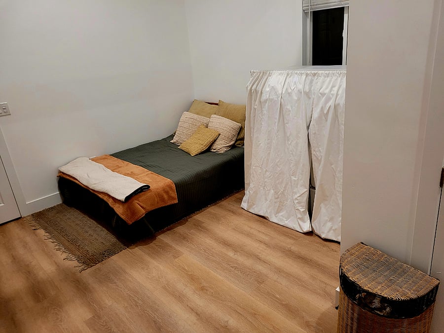 Full bed adjacent to washer-dryer in bedroom.