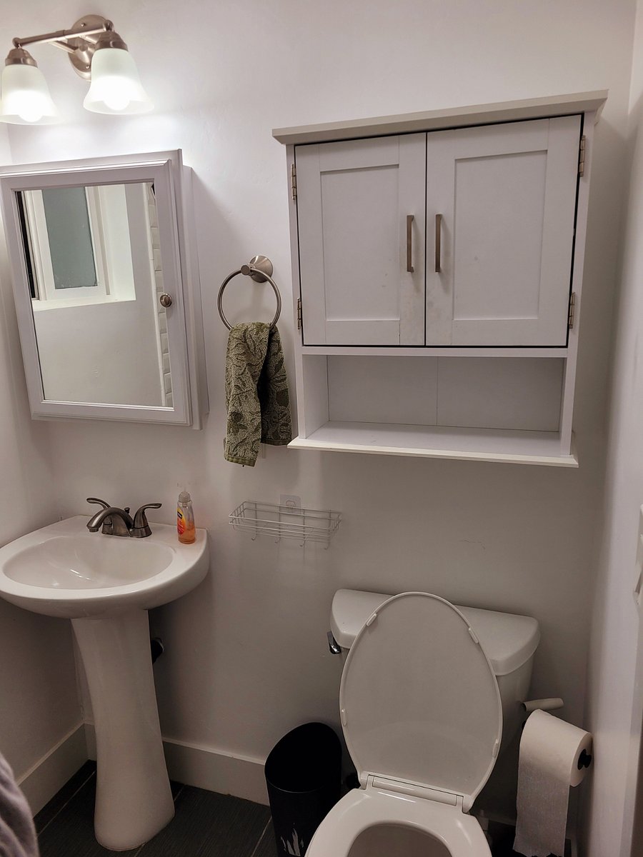 Bathroom with pedestal sink, medicine cabinet mirror, and cabinet storage.