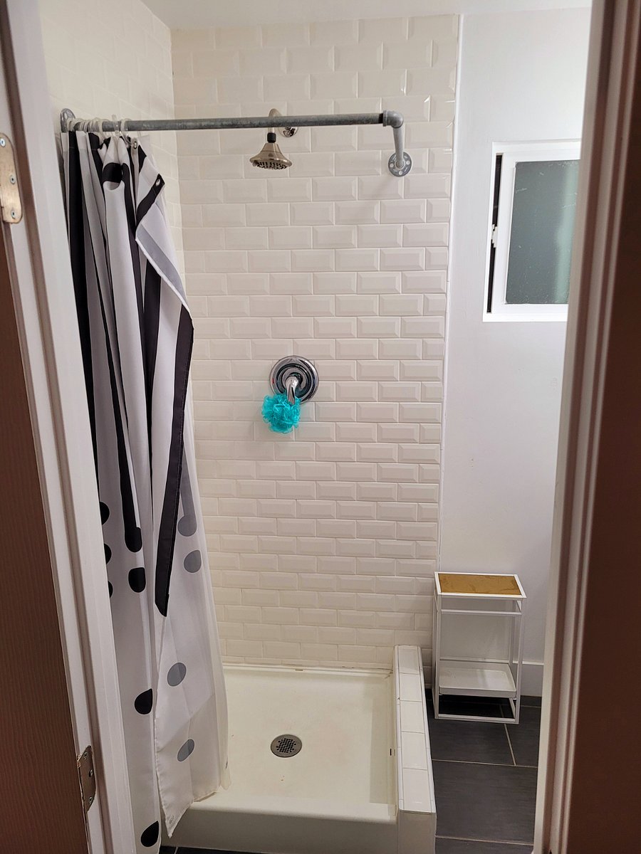 Step-in shower with subway tile and shower curtain.