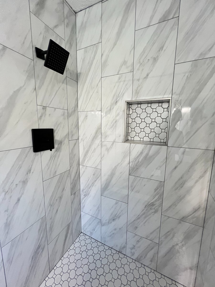 Large porcelain tiled master bathroom shower with gray slate tiled floor and shower niche.