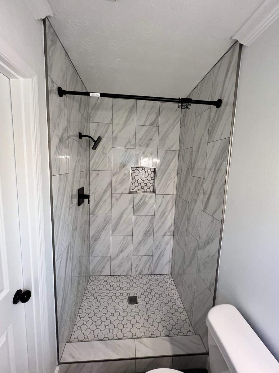 Large porcelain tiled master bathroom shower with gray slate tiled floor and shower niche.