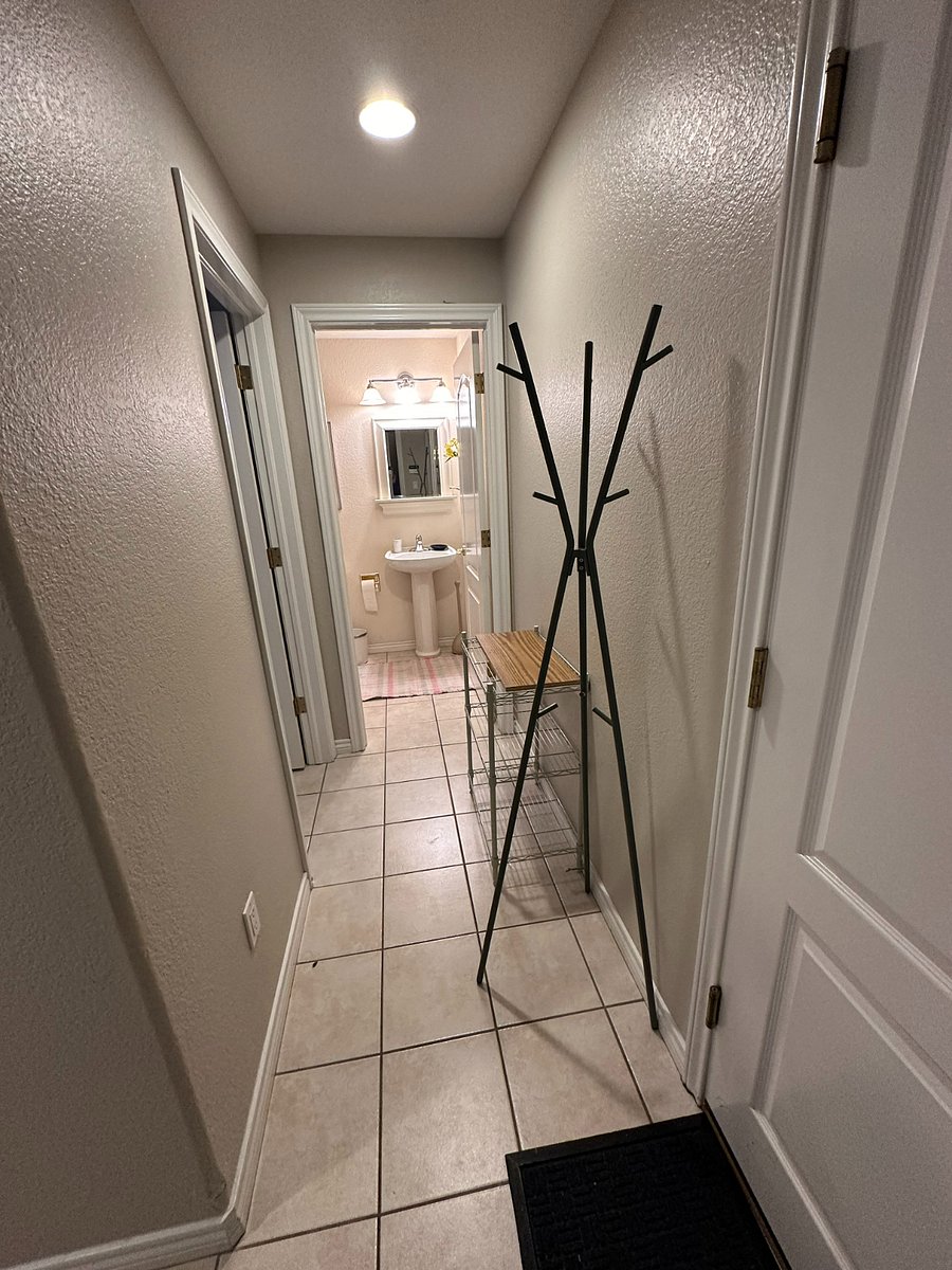 Hallway to private bathroom, with laundry room on the left, exit to garage on the right.