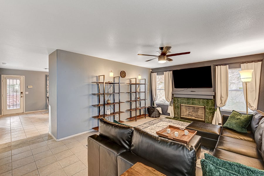 Living room with a large TV, a faux leather couch, and plenty of shelves
