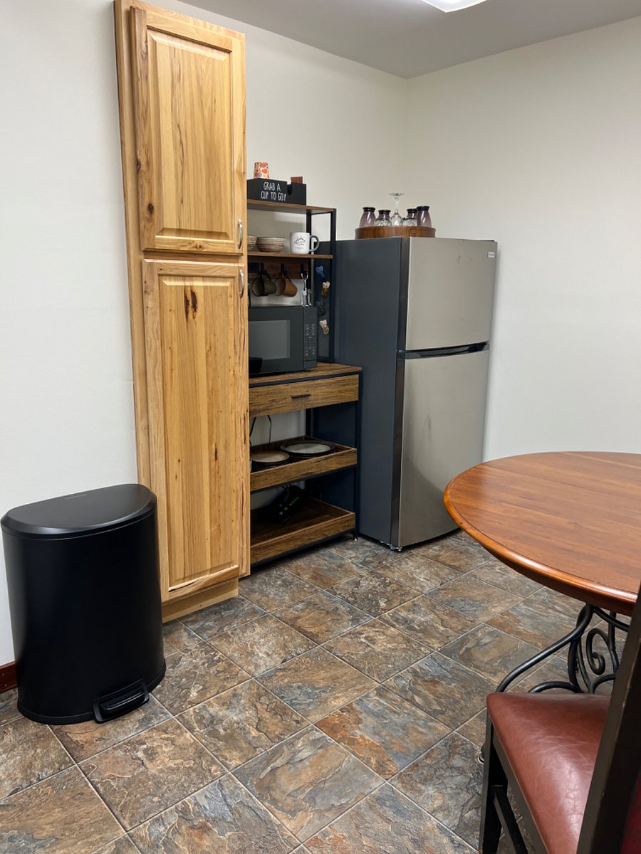 Private eating area inside suite with table and 2 chairs, full size refrigerator with freezer, microwave, keurig coffee maker, electric water kettle, dinnerware, silverware and food pantry.