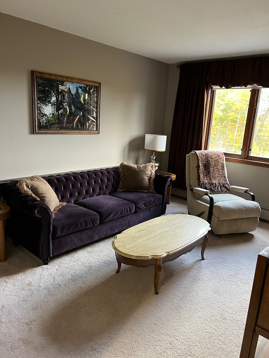 Living room with full size sofa, sofa table with two usb plug units, rocking recliner chair, marble coffee table, 50" smart tv, 2 end tables with 3-way lamps.