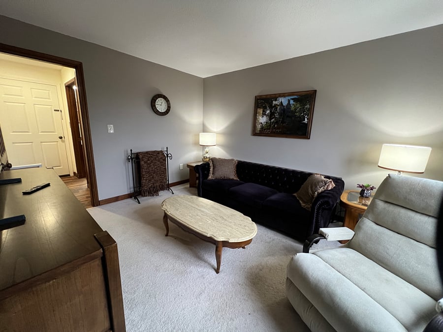 Living room with full size sofa, sofa table with two usb plug units, rocking recliner chair, marble coffee table, 50" smart tv, 2 end tables with 3-way lamps.