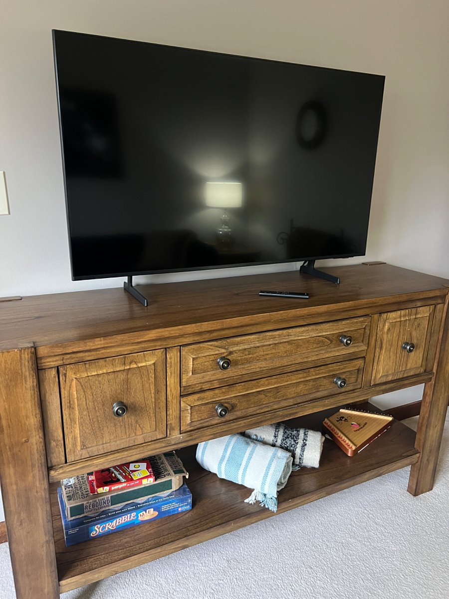 Living room with full size sofa, sofa table with two usb plug units, rocking recliner chair, marble coffee table, 50" smart tv, 2 end tables with 3-way lamps.