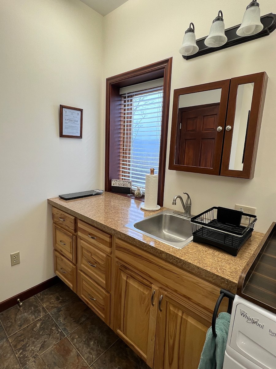 Private sink area inside suite with table and 2 chairs, full size refrigerator with freezer, stove/oven, microwave, keurig coffee maker, electric water kettle, dinnerware, silveware, and food pantry.