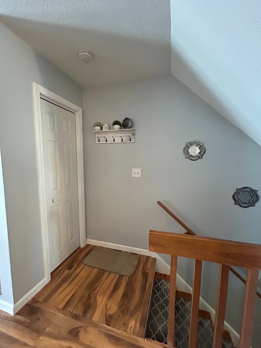 Top of the entrance stairwell with a coat rack and coat closet