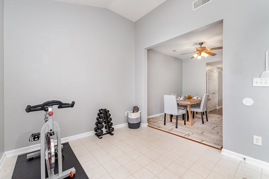 Dedicated fitness area includes: CAP Barbell free weight set, GIAIM yoga mat and blocks, stretching equipment (not shown), and Schwinn stationary bike