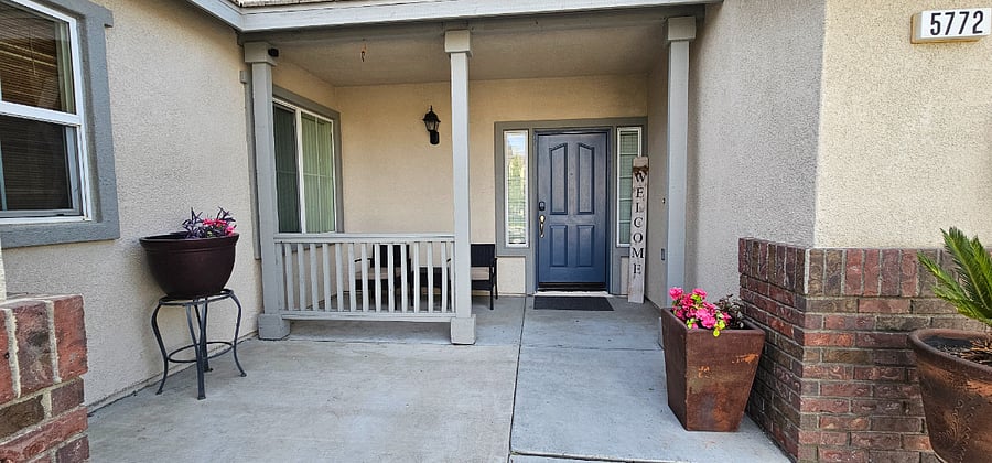Welcoming front porch with seating for two and a small coffee table, to wait outside for guests to arrive. 