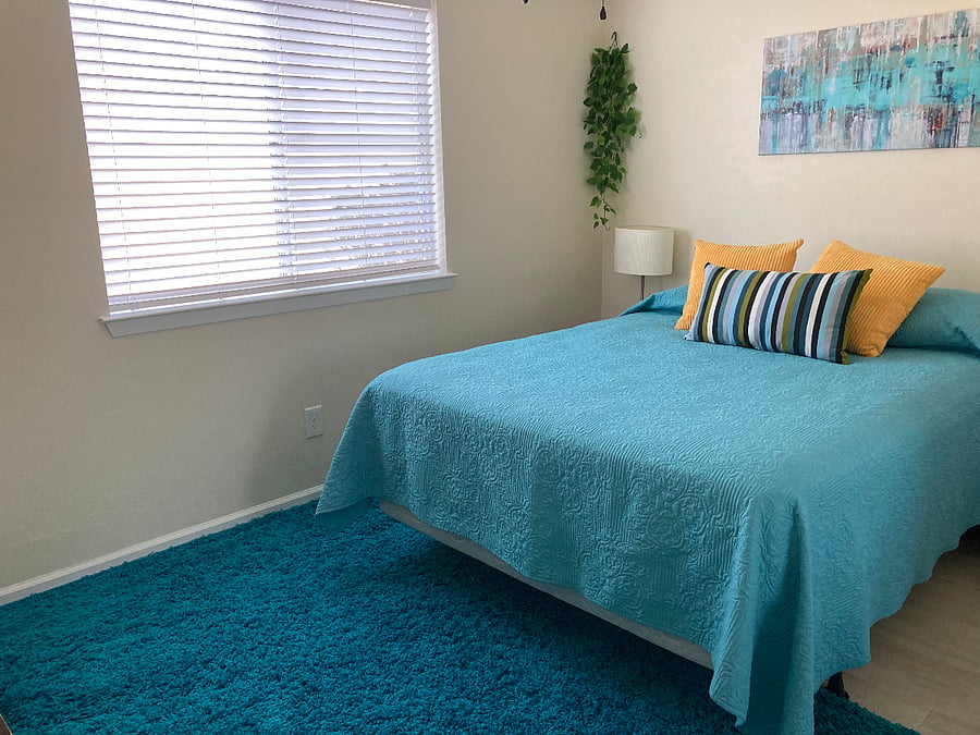 Second bedroom with queen bed and backyard view.
