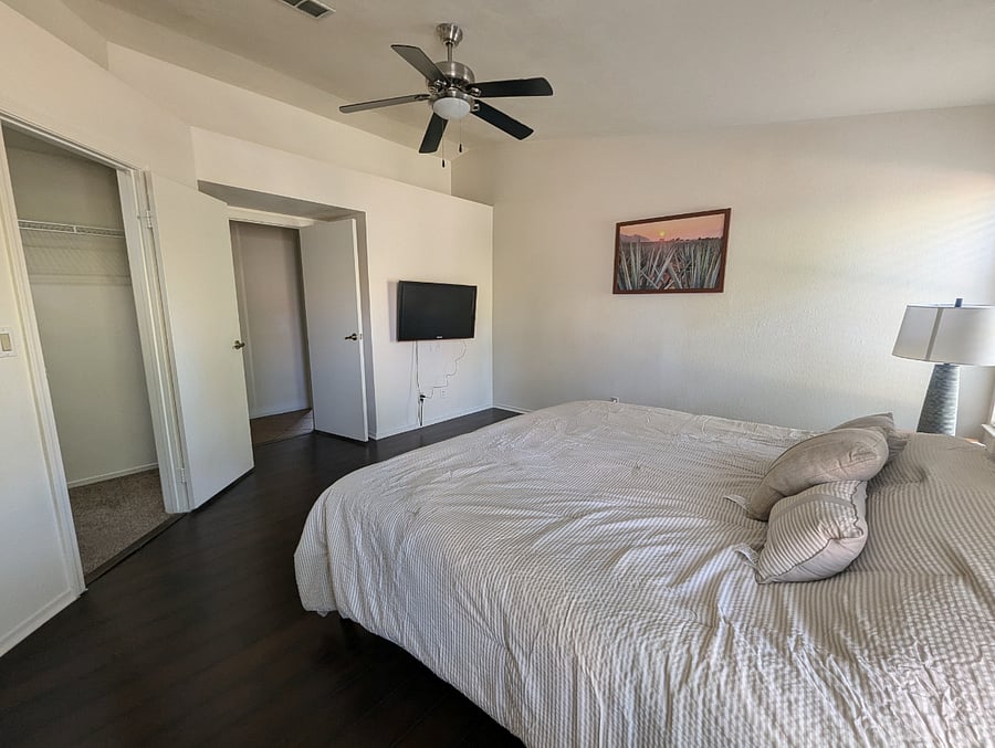 Spacious primary bedroom with walk-in closet and TV