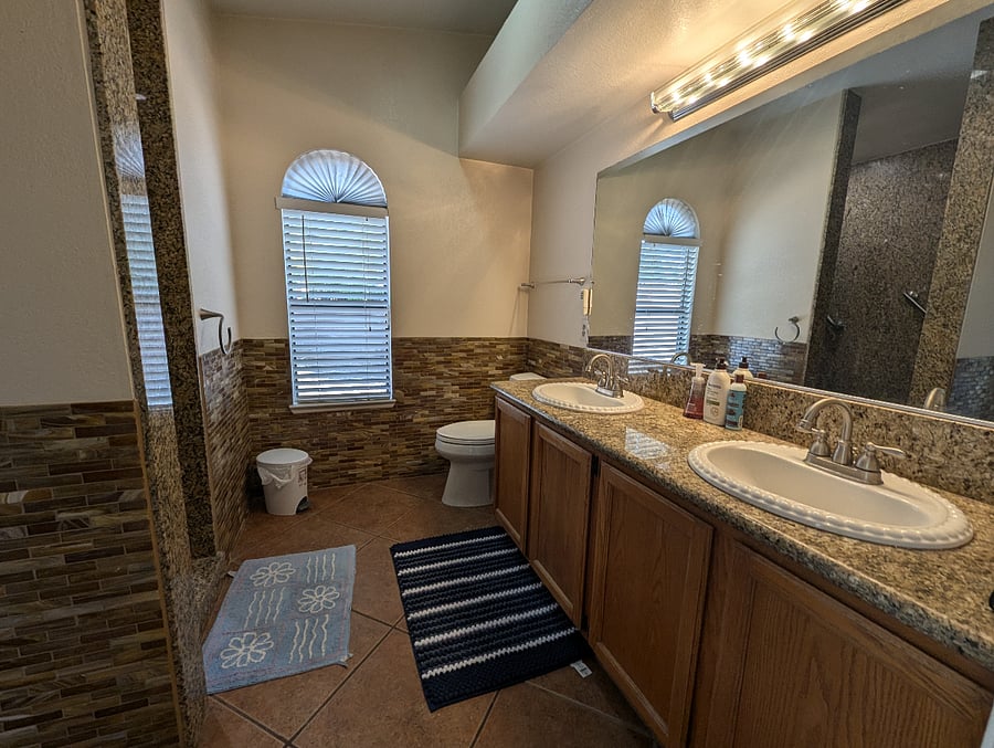 Private primary bathroom with shower, dual sink vanity and private entrance from the backyard.