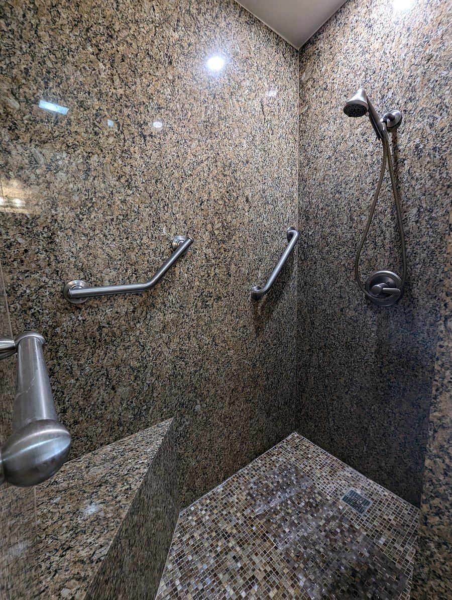 Primary shower featuring safety bars and corner seating