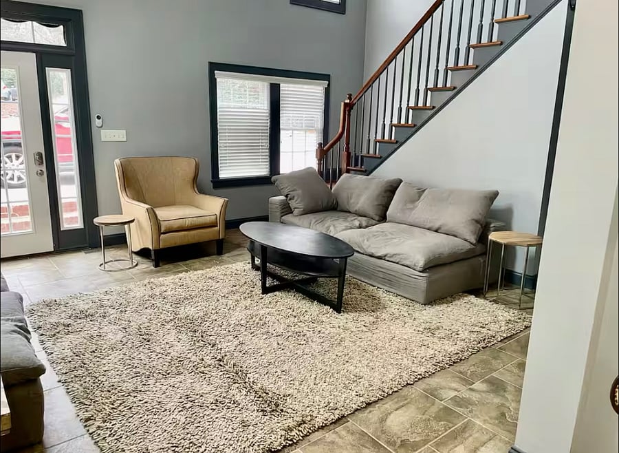 The airy living room has vaulted ceilings, tile floors, and comfy furniture for lounging, reading, or catching a game on the TV.