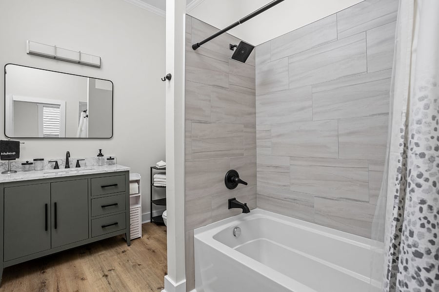 Stylish bathroom featuring a modern vanity, sleek black fixtures, and a tiled bathtub-shower combination for a clean and elegant look.