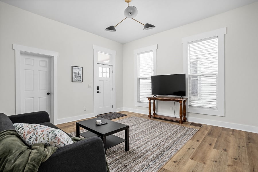Bright and inviting living room with a cozy sofa, sleek coffee table, and a TV on a wooden stand, featuring natural light and hardwood flooring.