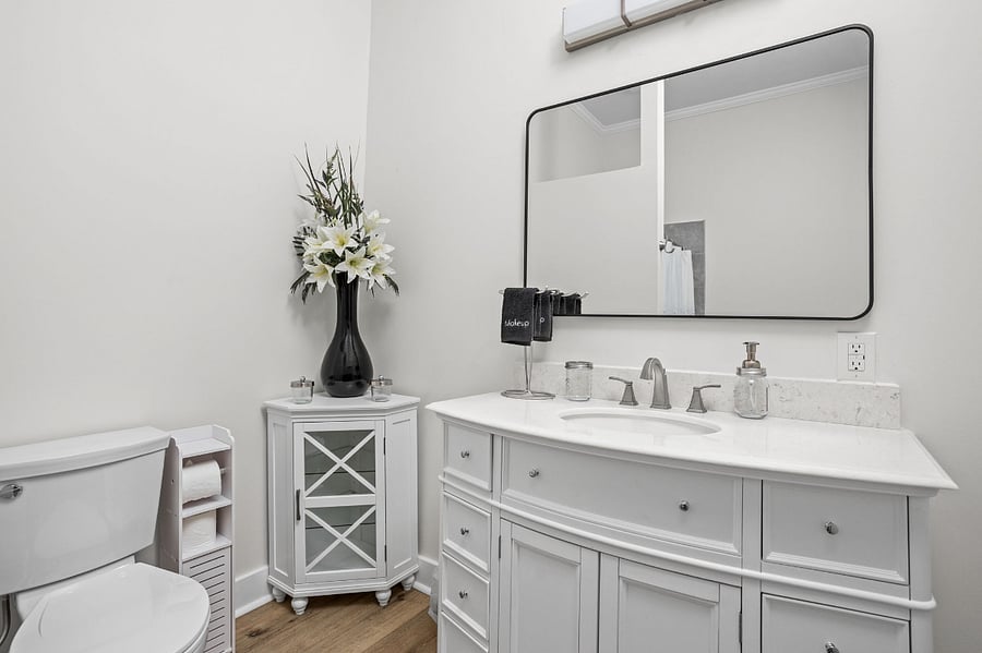 Elegant bathroom with a classic white vanity, a large framed mirror, and stylish decor, creating a bright and sophisticated space.