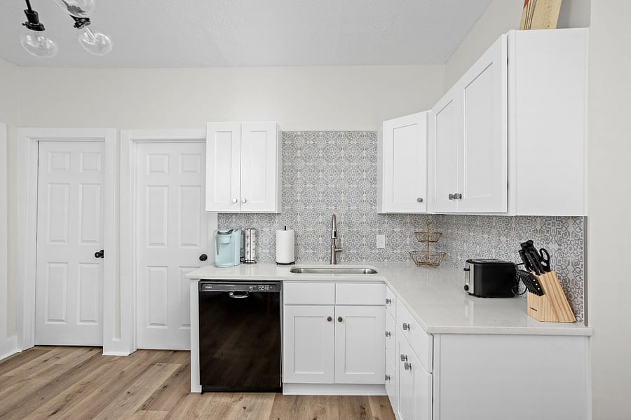Bright and modern kitchen with white cabinetry, patterned backsplash, and sleek appliances, creating a clean and stylish look.