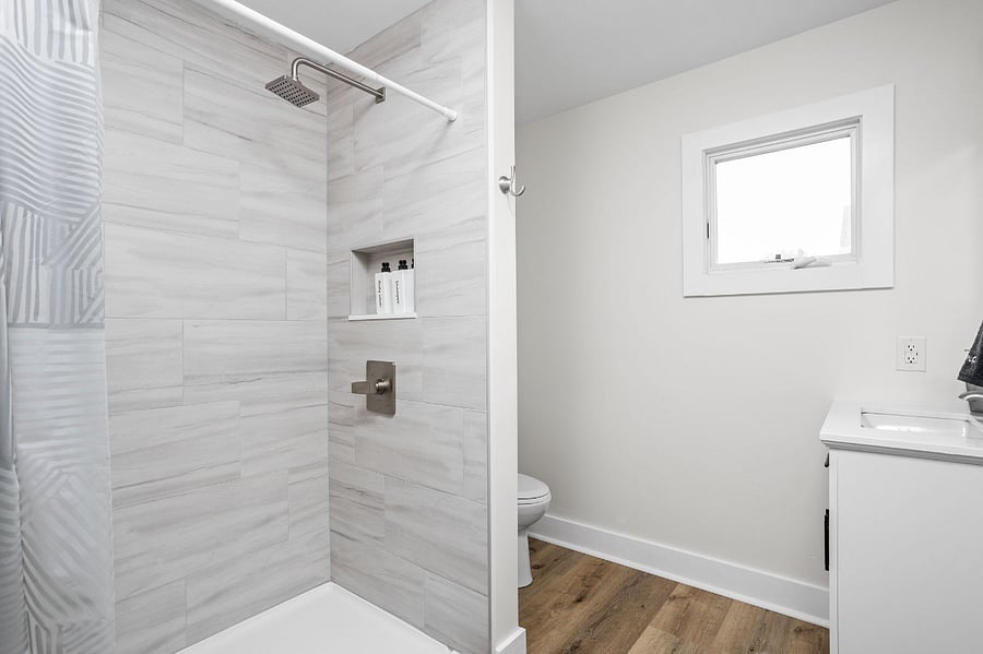 Sleek and modern bathroom featuring a tiled walk-in shower, built-in shelving, and a bright, minimalist design.
