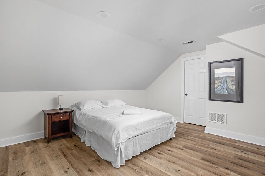 Cozy attic bedroom with a sloped ceiling, minimalist decor, and warm wooden flooring for a comfortable retreat.