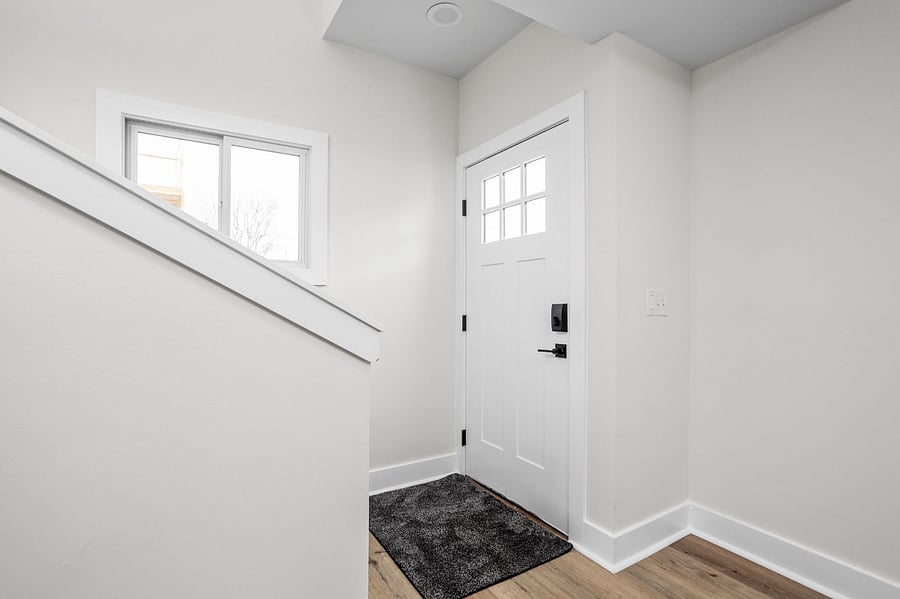 Bright and welcoming entryway with a modern white door, sleek black hardware, and a cozy minimalist design.