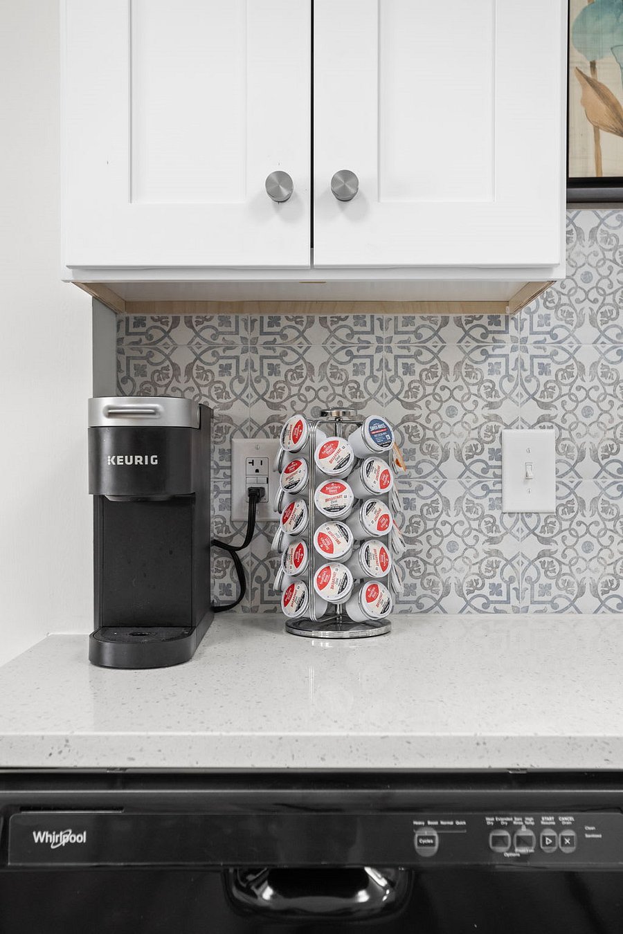 Stylish coffee station featuring a Keurig machine, organized coffee pod carousel, and a chic patterned backsplash.
