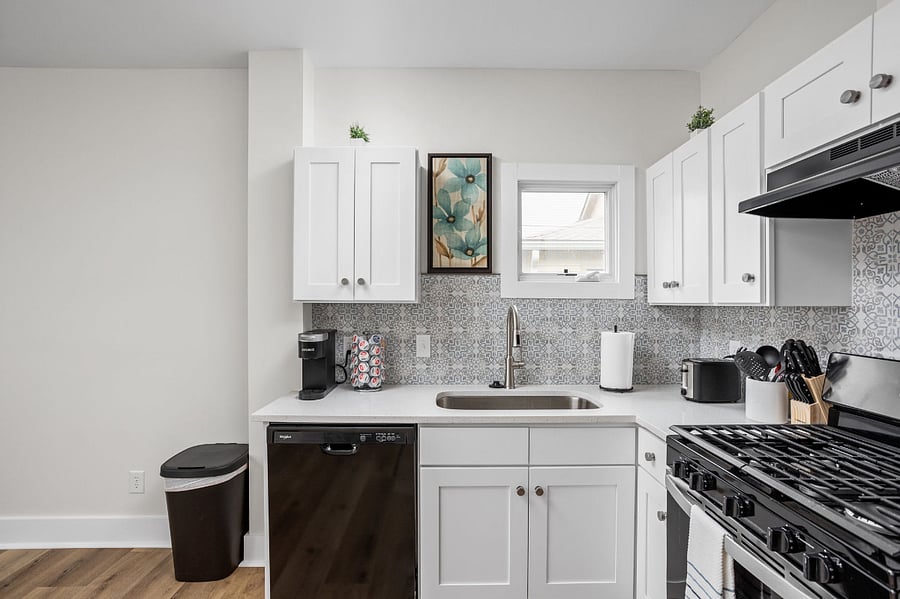 Elegant kitchen with white cabinetry, modern appliances, and a stylish backsplash adding a touch of sophistication.