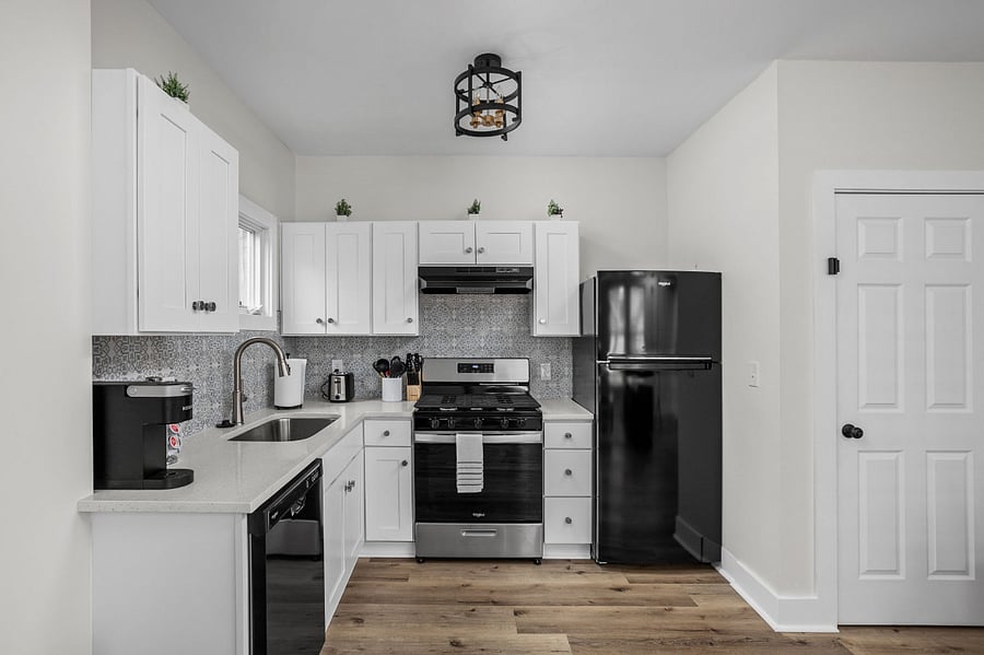 Stylish and functional kitchen featuring white cabinetry, modern black appliances, and a chic backsplash for a contemporary look.