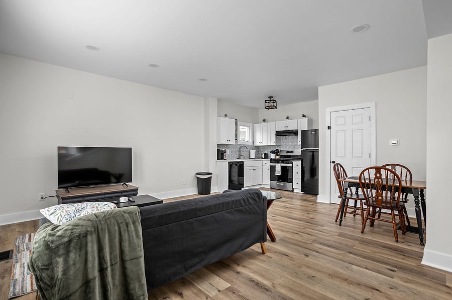 Modern open-concept living space featuring a cozy seating area, dining nook, and a sleek, fully-equipped kitchen with stainless steel appliances.