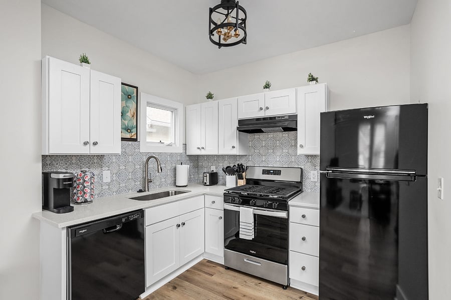 A charming and modern kitchen with white cabinetry, sleek black appliances, and a stylish backsplash for a contemporary touch.