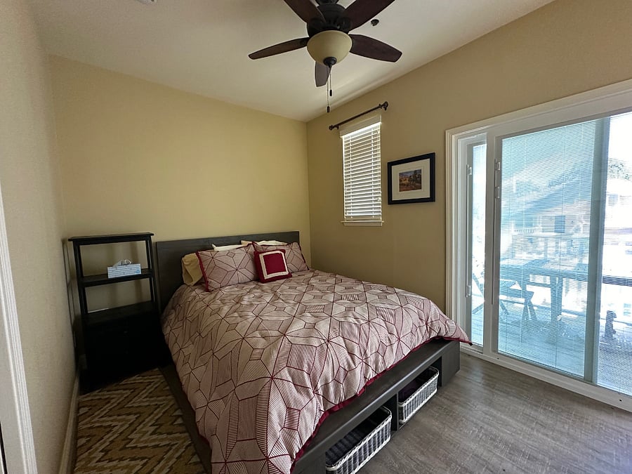 Bedroom with queen size bed and private balcony. Sliding glass door in bedroom has interior blinds that can be closed to darken room. 