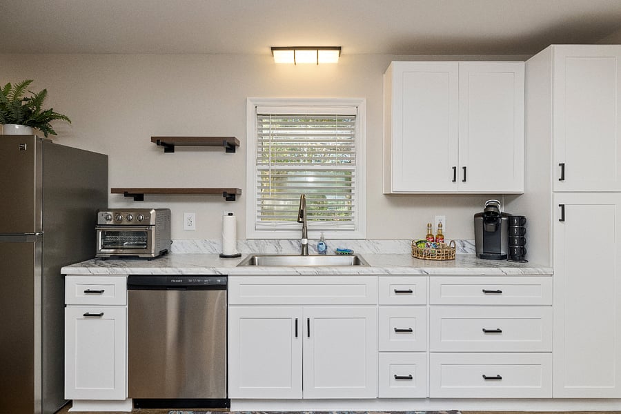The fully stocked kitchen includes a Keurig, a Cuisinart Air Fryer / Toaster Oven, a full-size fridge/freezer with an ice maker and dishwasher, pots, pans, mixing bowls, dishes, utensils, household essentials, and cleaning products.