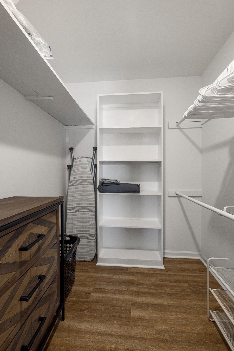 The walk-in closet has plenty of hangers, a full-size ironing board and iron, and a chest of drawers and laundry hamper.