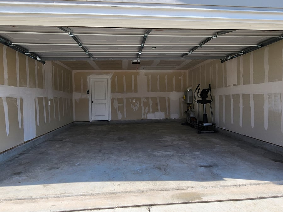 The two car garage with Elliptical exercise machine with a Eletric lawn mower to use to keep up keep of lawn   