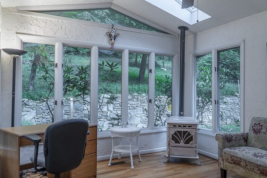 Cozy sun room with two dedicated work stations, lots of natural light, skylights, and a pellet stove