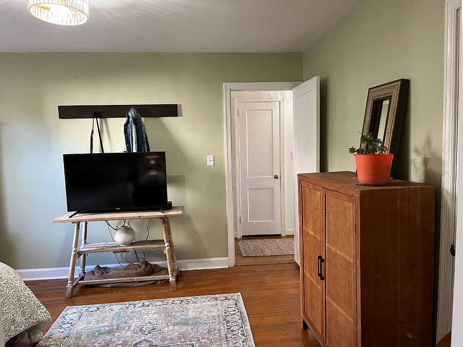 Thats a coat rack behind the tv. It has a Jean jacket and purse hanging from it. 